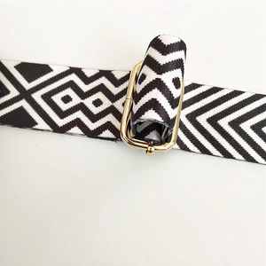 Close-up of black and white geometric canvas bag strap with golden metal adjustment buckle