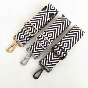 Detail of adjustable black and white geometric canvas bag straps with gold, silver and black hooks
