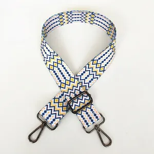 Detail view of woven geometric bag strap in blue and yellow with metal swivel hooks