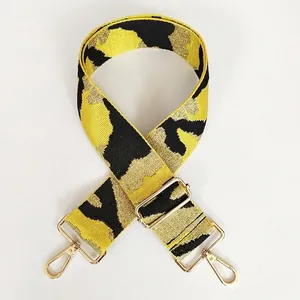 Detail of adjustable woven bag strap with yellow gold-thread animal pattern and gold hooks