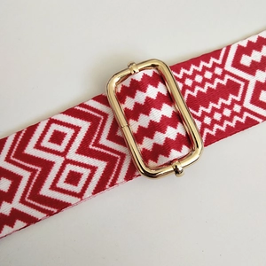 Macro detail of red and white ethnic woven bag strap with golden metal buckle