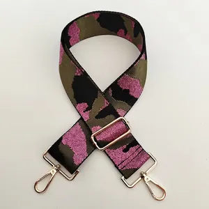 Detail of adjustable wide camouflage strap with golden metal hardware and lobster clips