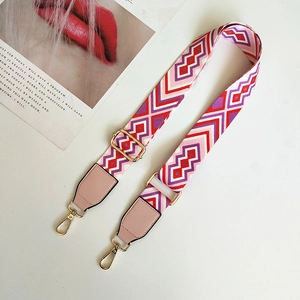 Detail of colorful geometric woven strap with gold metal hooks and pink faux leather ends