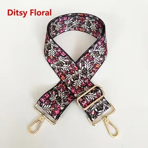 Detail of floral canvas bag strap with gold metal hooks and navy flower pattern