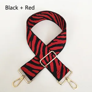 Detail of red and black zebra print wide nylon shoulder strap with gold swivel hooks