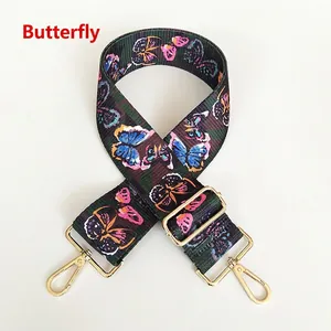 Detail view of canvas handbag strap with colorful butterfly prints and gold metal hooks