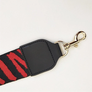 Close-up of zebra pattern woven shoulder strap with gold metal lobster clasp and black leather