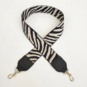 Detail of black and off-white zebra pattern wide strap with golden metal hooks