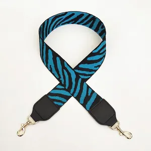 Close-up of zebra pattern woven shoulder strap with gold lobster clasps and leather ends