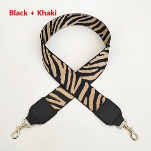 Detail of wide zebra pattern bag strap with black leather ends and golden metal hooks