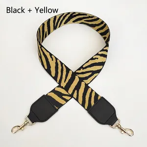 Close-up of black and yellow zebra pattern woven bag strap with gold metal spring buckles