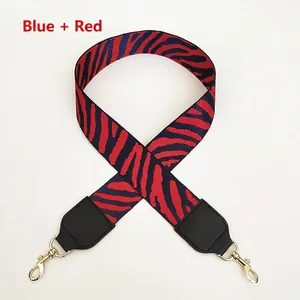 Detail of blue and red tiger stripe canvas bag strap with golden lobster clasps