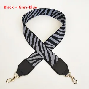 Close-up of zebra pattern handbag strap with black and grey-blue fabric and gold metal hook