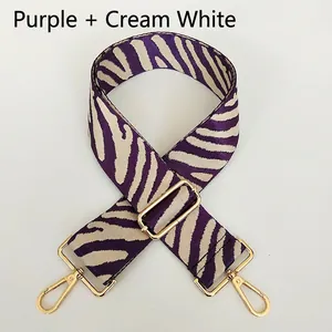 Detail of purple and cream zebra pattern woven bag strap with golden metal snap hooks