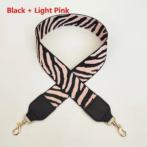 Detail of zebra pattern bag strap in black and light pink with gold metal swivel hooks