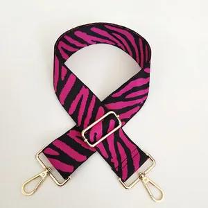 Detail of zebra pattern canvas strap in black and magenta with golden metal hooks