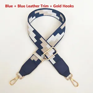 Detail of adjustable blue geometric embroidered bag strap with gold metal hooks and leather