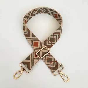Close-up of adjustable wide woven shoulder strap with geometric diamond embroidery and gold hooks