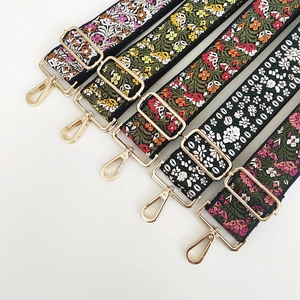 Detail of five floral embroidered bag straps with premium gold metal adjustment hooks