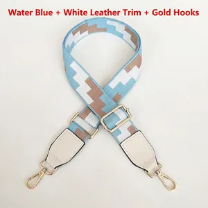 Detail of light blue embroidered bag strap with white leather ends and gold metal hooks