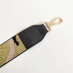 Detail of adjustable woven bag strap with golden lobster clasp and wave pattern texture