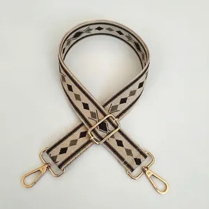 Detail of adjustable woven bag strap with geometric rhombus pattern and gold hooks