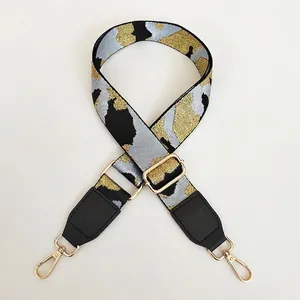 Macro detail of camo embroidered handbag strap with black leather ends and gold buckle