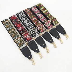 Close-up of six ethnic embroidered wide bag straps with golden metal hooks and floral patterns