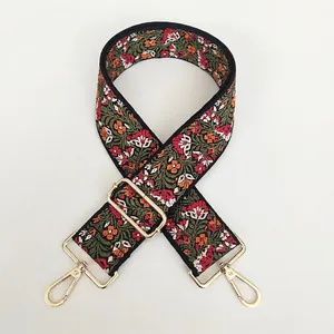 Detail of floral embroidered wide purse strap with polished light gold lobster clasps