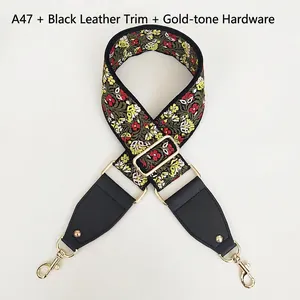 Close-up of wide floral embroidered handbag strap with black leather and gold hooks