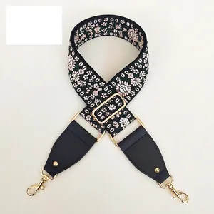 Macro detail of floral embroidered wide strap with black leather and gold metal hooks
