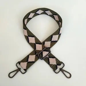 Detail of adjustable bag strap with olive green diamond pattern and gunmetal hooks