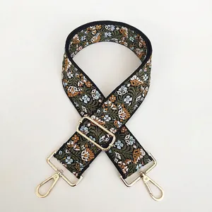 Detail of floral embroidery on wide green shoulder strap with gold metal lobster clasp