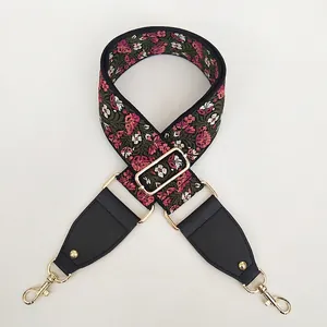 Close-up of ethnic floral embroidery on a wide shoulder strap with gold hardware