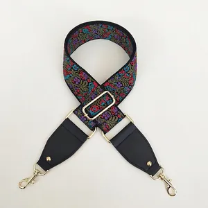 Detail of colorful floral embroidery strap with black leather ends and gold metal hooks