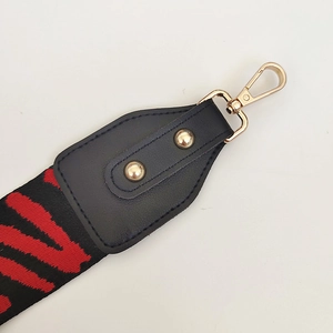 Detail of red and black geometric strap with golden rivets and premium lobster clasp