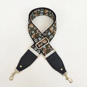 Close-up of ethnic style floral woven bag strap with golden metal hooks and leather trim