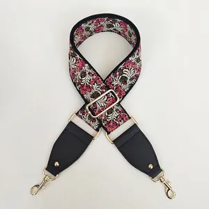 Detail of floral embroidered wide shoulder strap with black leather and gold metal hooks