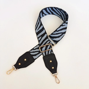 Detail of adjustable zebra stripe bag strap with gold rivets and leather ends