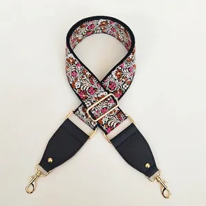 Detail view of ethnic floral embroidered wide bag strap with gold hooks and black leather tips