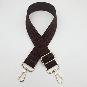 Detail of adjustable houndstooth weave bag strap with light gold metal lobster clasps
