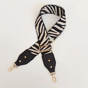 Close-up of zebra pattern adjustable strap with gold rivets and lobster clasps