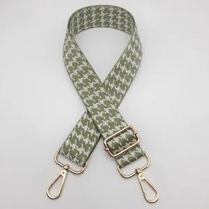 Detailed view of green houndstooth jacquard bag strap with gold metal lobster clasps