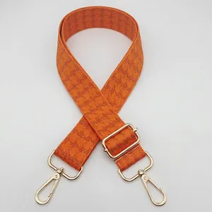 Detail of adjustable wide bag strap with orange and brown houndstooth jacquard pattern