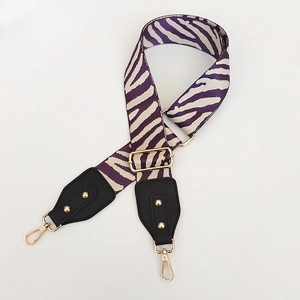 Detail of adjustable purple zebra pattern wide canvas shoulder strap with gold hardware