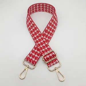 Close-up of houndstooth jacquard bag strap with adjustable gold metal buckle hardware
