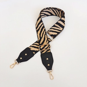 Detail of adjustable zebra print bag strap with golden rivets and black leather ends