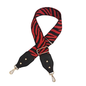 Adjustable red and black zebra print bag strap with golden rivets and black leather ends
