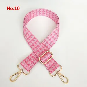 Close-up of pink houndstooth jacquard wide bag strap with golden metal swivel hooks