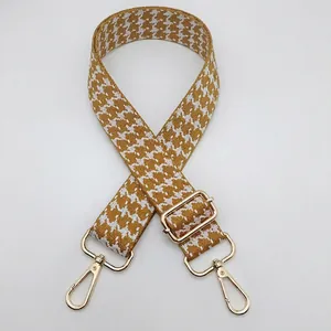 Detail view of mustard yellow houndstooth pattern wide woven bag strap with gold buckles